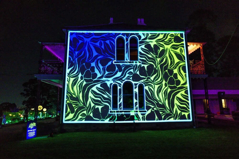Two visitors walking a glowing light corridor at Echoes Moon Garden